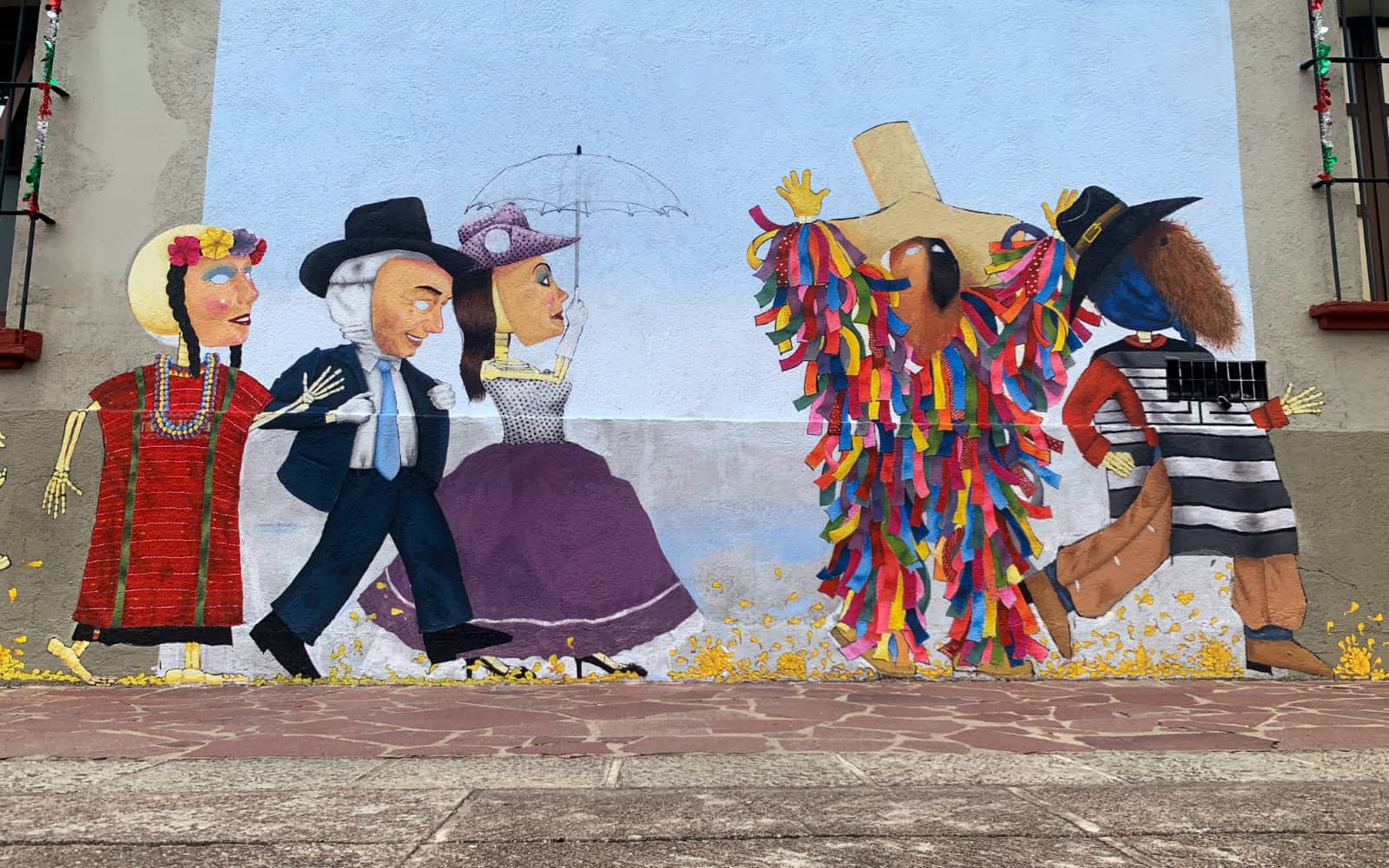 Five colourful figures painted on the wall of a stone building