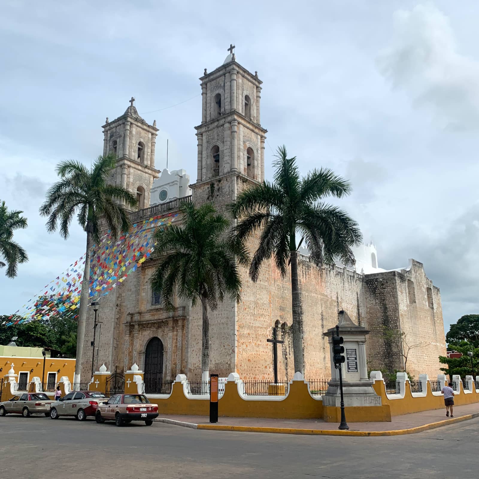 Large stone church with colourful flags and palm trees in front